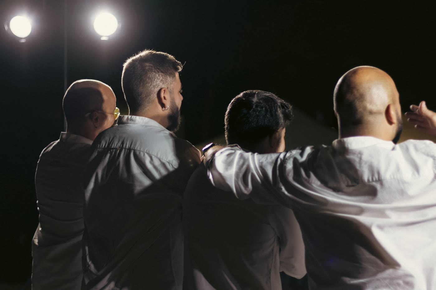 Los integrantes de El Chamelo abrazados de espaldas ante el público